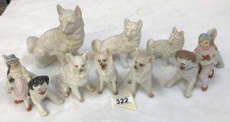 A quantity of bisque porcelain dogs including a pair with boy and girl figures