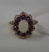 A floral head 9ct gold dress ring with petals of purple stones and central opal. size O.