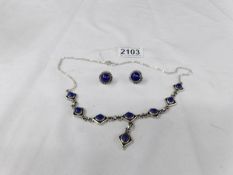 A silver necklace and earrings set blue stones.