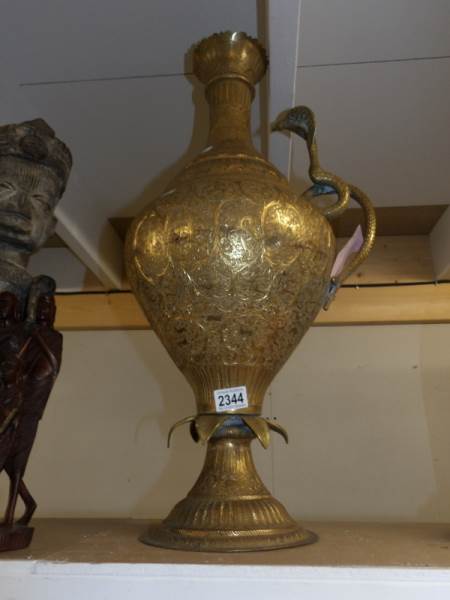 A large brass ewer with cobra handle.