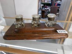 An Edwardian oak ink stand with 3 glass ink wells.