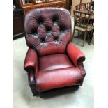 A deep red leather manual reclining arm chair