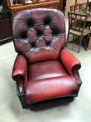 A deep red leather manual reclining arm chair