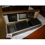 A wooden box containing approximately 50 black and white glass lantern slides of farming and