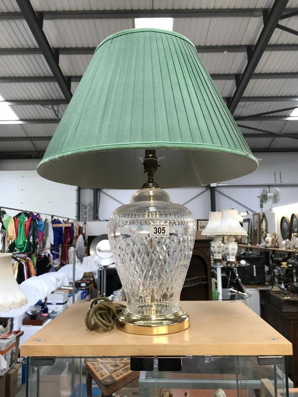 A large cut glass table lamp with brass fittings and green shade