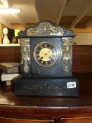 A black slate mantel clock with brass or metal decoration.