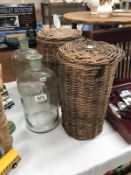 A pair of glass storage bottles in wicker containers
