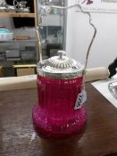 A cranberry glass biscuit barrel with plated top and handle.