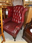 A red deep buttoned wing arm chair.