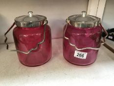 A pair of cranberry glass biscuit barrels with silver plated fittings