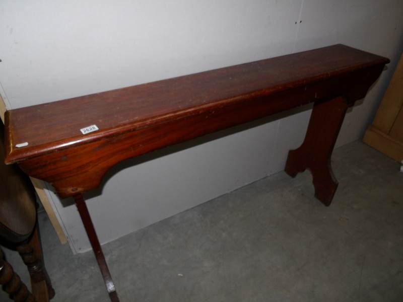 A dark stained pine bench,.