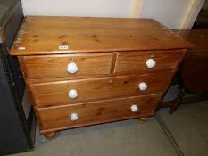 A Victorian pine chest of drawers with porcelain knobs.