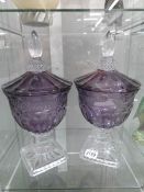 A pair of amethyst coloured glass lidded goblets on clear bases.