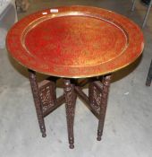 A brass topped folding Arabic table with red enamelling.