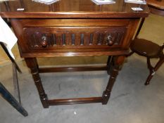 A dark oak side table with drawer.