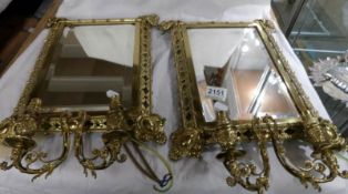 A pair of ornate brass framed mirror with double wall lights.