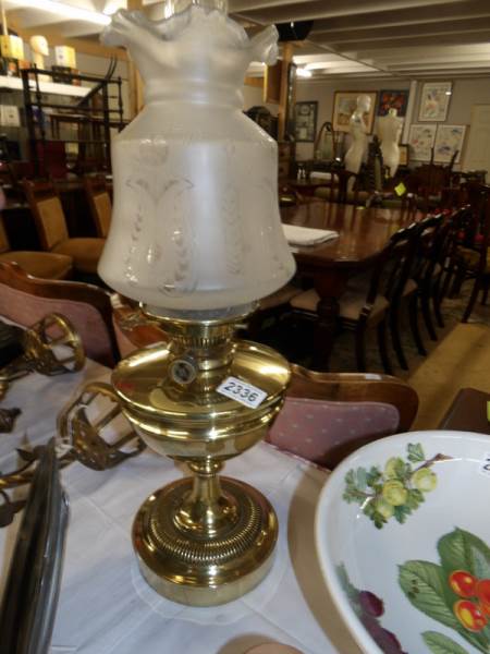 A brass oil lamp with etched shade.