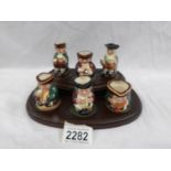 A set of 6 Royal Doulton Toby jugs on stand.