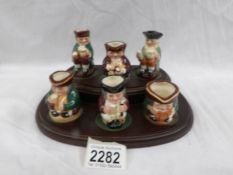 A set of 6 Royal Doulton Toby jugs on stand.
