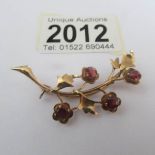 A 9ct gold floral brooch set red stones.