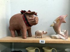 A carved stone dolphin group plus a pig and large terracotta pig.