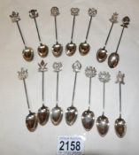 14 white metal teaspoons with coat of arms finials.