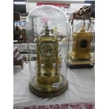 A brass 4 column clock under glass dome.