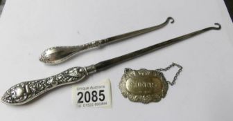 A large silver handled button hook, a smaller example and a silver wine label.