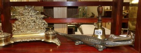 A brass inkwell, a brass school bell and a bronze crocodile nut cracker.