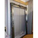 A large silver coloured ornate mirror/picture frame.