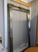 A large silver coloured ornate mirror/picture frame.