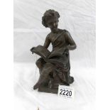 A bronze figure of a child reading.