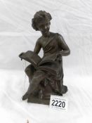 A bronze figure of a child reading.