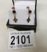 A pair of early 20th century garnet set ear pendants in gold.