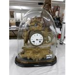 A French gilt clock under glass dome.