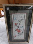 A framed and glazed embroidery depicting flowers and birds.