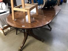 A dark wood stained extending dining table with brass paw feet castors