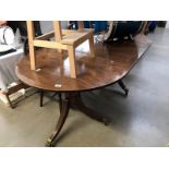 A dark wood stained extending dining table with brass paw feet castors