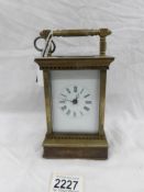 A brass carriage clock with decorated side panels.