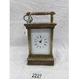 A brass carriage clock with decorated side panels.