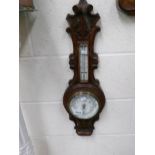 A carved oak aneroid barometer.