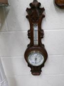 A carved oak aneroid barometer.