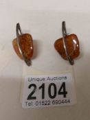 A pair of amber ear pendant set in silver, unusual design.