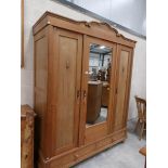 A 3 door pine wardrobe with central mirrored door.