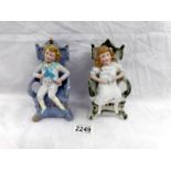A pair of bisque porcelain figures of boy and girl on chairs (boy a/f).