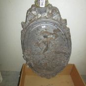 An oval lead wall plaque depicting cherubs.