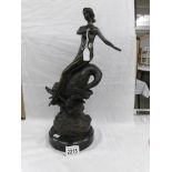 A bronze figure of a nude riding a dolphin.