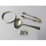 A silver sauce ladle, silver sugar nips and silver bangle.