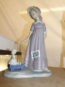 A Lladro figurine of a girl with a doll in a cart.