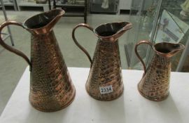 A set of 3 graduated copper jugs.
